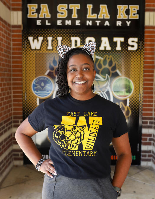 Dr. Jasmine Farrow Principal at east lake elementary in front of school with ears on in east lake shirt